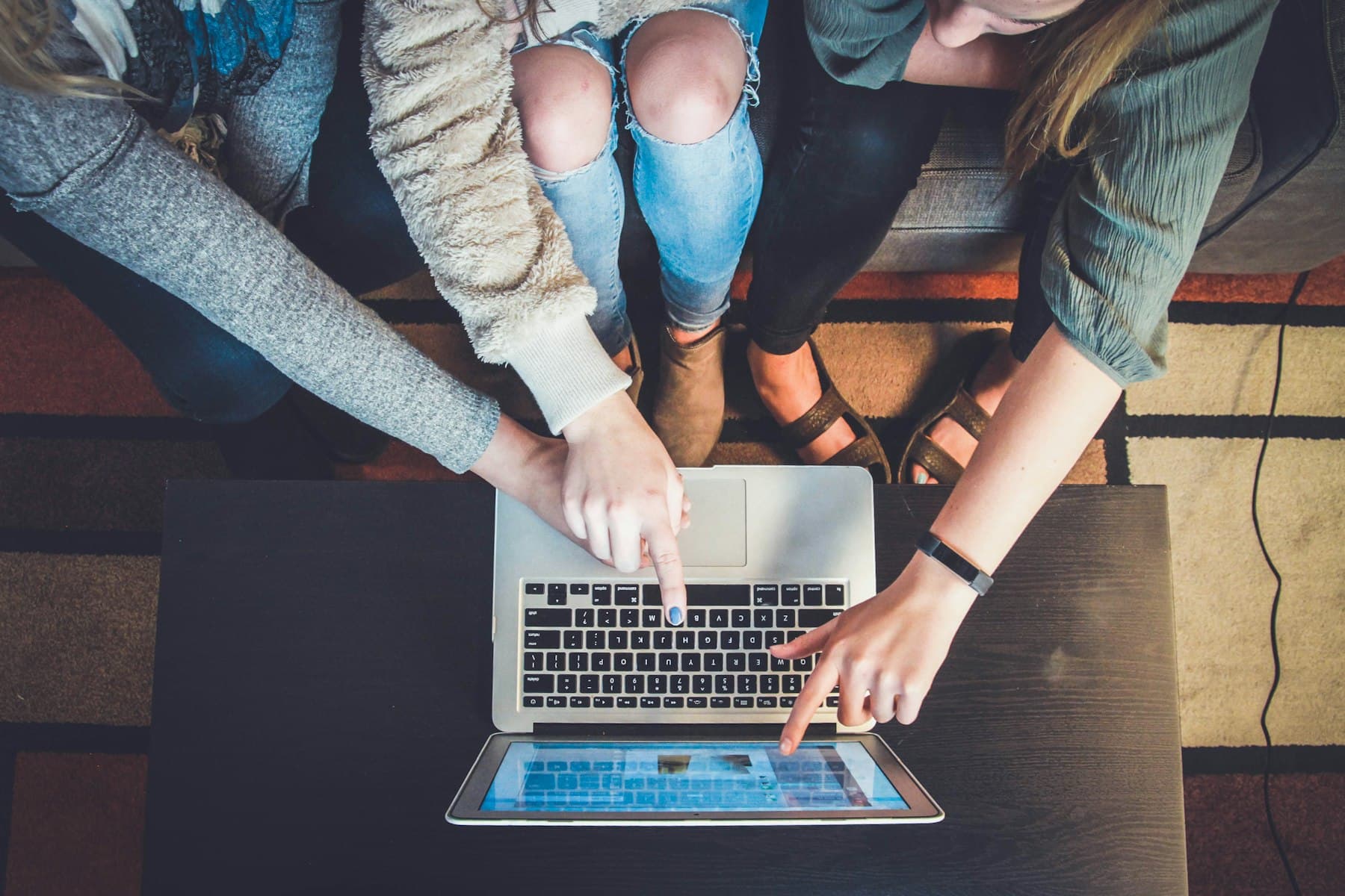 Three learners working through code together on one laptop